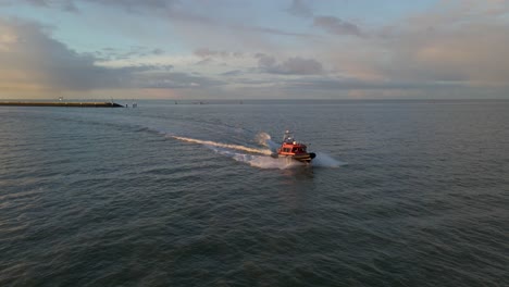 Boat-leaving-inlet-from-Harlingen-harbor-moving-out-to-open-sea,-aerial