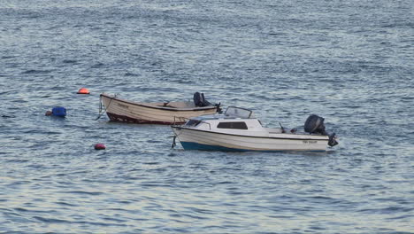 Kleine-Hölzerne-Fischerboote,-Die-Auf-Dem-Rauen-Und-Gekräuselten-Meerwasser-Schwimmen