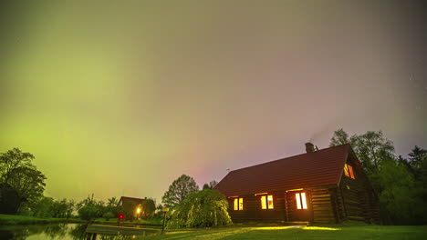 Northern-lights-above-log-cabin-house-in-rural-countryside-timelapse-on-misty-night