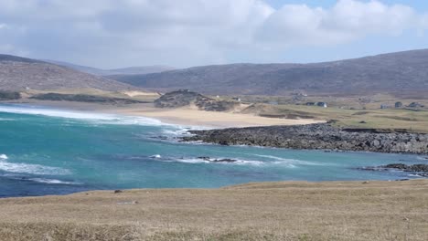 Pan-De-Impresionante-Océano-Azul-Turquesa-Con-Olas-Rodando-Hacia-El-Paisaje-Rural-Costero-En-La-Isla-De-Lewis-Y-Harris,-Hébridas-Exteriores,-Escocia-Occidental,-Reino-Unido