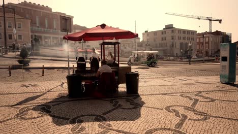 Woman-Roasting-Chestnuts,-People-Walking-with-Masks-on-and-a-Hand-Sanitazing-Station