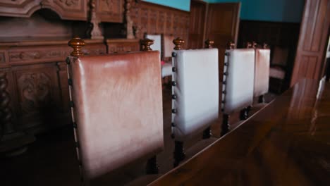 Row-of-antique-leather-backed-chairs-facing-an-intricately-carved-buffet-in-the-grand-dining-room-of-Trakošćan-Castle,-Croatia