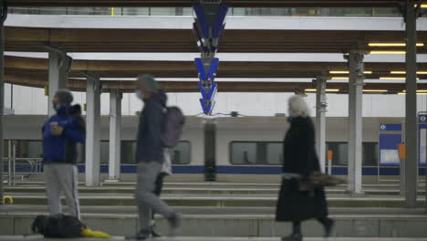 People-walk-along-a-train-station-platform