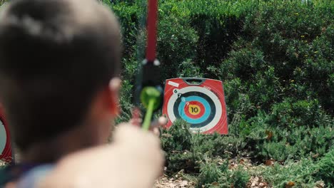 Slow-motion-over-the-shoulder-shot-of-a-child-playing-archery-and-shooting-arrows
