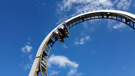 People-riding-a-roller-coaster,-slow-motion-as-they-enter-a-loop