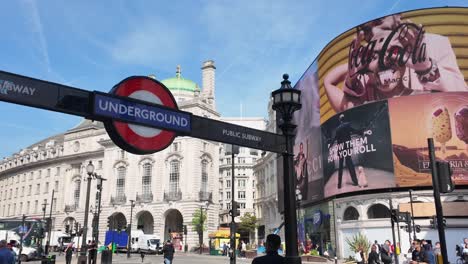 Piccadilly-Circus-Con-Letrero-Del-Metro-De-Londres-Y-Multitud-Bulliciosa-En-Un-Día-Soleado,-Con-Destacados-Carteles-Digitales