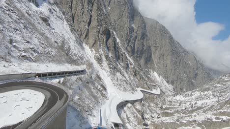 Ferrari-in-the-alps-driving-fast-along-a-mountain-pass-tunnel-high-speed-drone-view