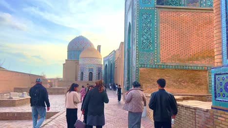 Usbekische-Erwachsene-Frauen-In-Nationalkleidung-Gehen-Und-Schauen-Sich-Die-Fassade-Einer-Alten-Moschee-Auf-Dem-Registan-Platz-In-Samarkand-An