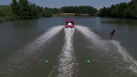 Female-water-skier-extreme-sport-surfing-behind-speeding-boat-at-Monaco-ski-lake