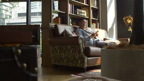 asian-man-looks-on-phone-in-contemporary-cafe