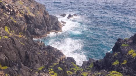 Rocky-cliff-and-the-churning-of-the-Atlantic-Ocean-from-above,-Los-Roques-Venezuela