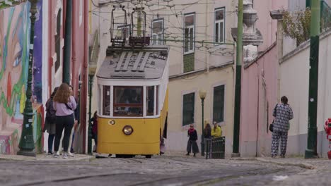 Famous-vintage-yellow-trams-driving-up-the-slope-of-Elevador-da-Glo-ria-in-Lisbon,-Portugal