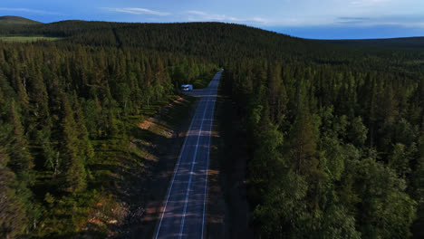 Drone-tilting-toward-a-RV-wild-camping-on-a-parking-lot-in-Lapland,-summer-sunset