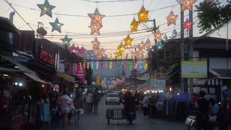 Mehrere-Touristen-In-Sommerkleidung-Shoppen-Auf-Der-Anderen-Straßenseite-Mit-Ladenständen-An-Einem-Warmen-Sommerabend-In-Der-Stadt-Pai-In-Thailand