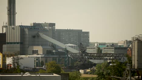 Industrial-skyline-with-coal-conveyor-and-modern-buildings-on-a-sunny-day,-wide-shot