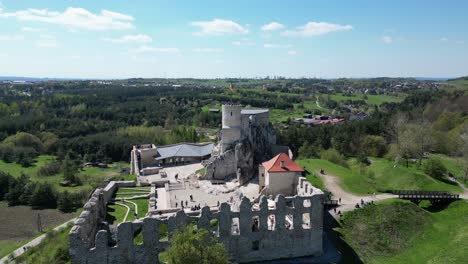 Castillo-Medieval-De-Rabsztyn-Con-Una-Torre,-Murallas-Y-Un-Patio-Durante-Un-Hermoso-Día-De-Verano-Rodeado-De-Exuberante-Vegetación,-Hierba-Y-árboles-Bajo-Un-Cielo-Azul-Claro