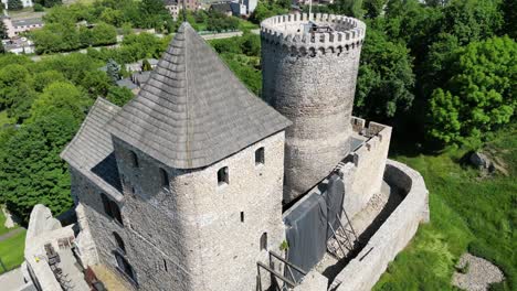 Medieval-castle-with-a-tower,-walls,-and-courtyard-during-a-beautiful-summer-day-surrounded-by-lush-greenery