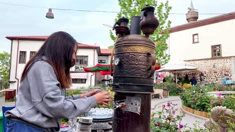 Ankara,-Türkiye:-A-young-woman-preparing-tea-in-a-traditional-way-at-a-square-in-Trabzon-Castle