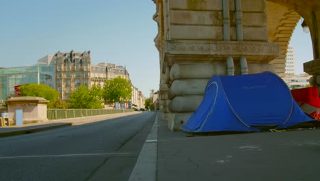 A-small-camp-of-homeless-refugees-sleeping-in-tents-under-a-railroad-at-Bir-Hakeim-Bridge-in-an-intersection-in-Paris,-France