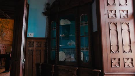 Antiker-Holzschrank-Mit-Glastüren,-Die-Keramik-Reflektieren,-Eingebettet-In-Eine-Leuchtend-Blaue-Wand-Im-Speisesaal-Des-Schlosses-Trakošćan