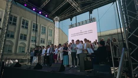 Coro-De-Alumnos-Letones-Cantando-En-El-Escenario-Al-Aire-Libre-En-La-Escuela-Secundaria-Durante-La-Celebración