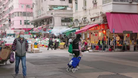 Die-Einheimische-Asiatische-Bevölkerung-Erledigt-Ihre-Einkäufe-Und-Läuft-über-Die-Straße,-Während-Taxis-Und-Ein-Bus-Des-öffentlichen-Nahverkehrs-An-Der-Kreuzung-Nach-Links-Abbiegen