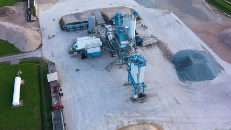 Asphalt-mixing-machine-in-an-asphalt-factory,-mounds-of-crushed-stone-as-the-main-material