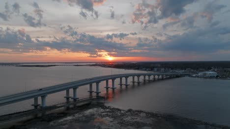 Aerial-drone-forward-moving-shot-of-traffic-movement-over-a-bridge-at-sunset-along-the-bay-area