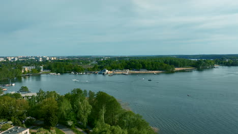 Una-Vista-Panorámica-Del-Lago-Ukiel-En-Olsztyn-Con-Una-Mezcla-De-Desarrollo-Urbano-Y-Exuberante-Vegetación-A-Lo-Largo-De-La-Costa