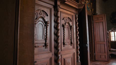 Dormitorio-Del-Conde-En-El-Castillo-De-Trakošćan,-Con-Puertas-De-Madera-Intrincadamente-Talladas-Con-Columnas-Retorcidas-Y-Paneles-Decorativos,-Que-Reflejan-La-Habitación-En-Un-Espejo-Ornamentado