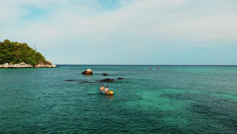 Aerial-orbit-of-couple-in-a-kayak-paddling-around-turquoise-blue-sea-near-tropical-island-in-Thailand