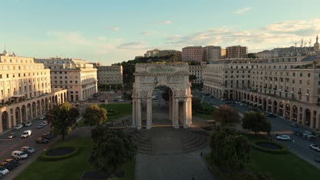 Aerial-view-of-traffic-around-Genoa's-monumental-arch-at-sunset