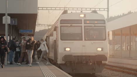 Train-passengers-getting-off-train-stopped-at-outdoor-station-in-Switzerland