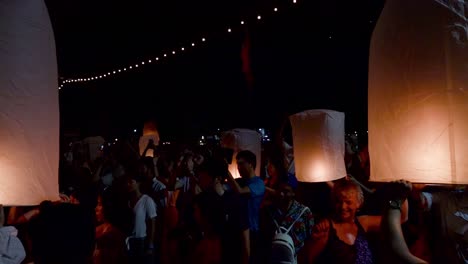 Tourists-holding-floating-lanterns-with-excitement-before-releasing-them-into-the-night-sky-during-Yi-Peng-Festival-in-Chiang-Mai,-Thailand