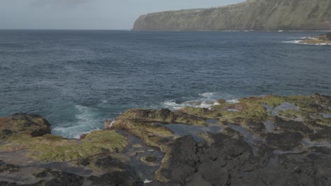 Rugged-volcanic-coastline-of-Mosteiros,-Sao-Miguel-with-crashing-waves-and-lush-cliffs