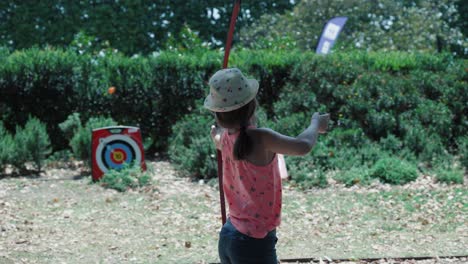 Slow-motion-shot-of-a-young-girl-taking-aim-and-firing-at-a-archery-target