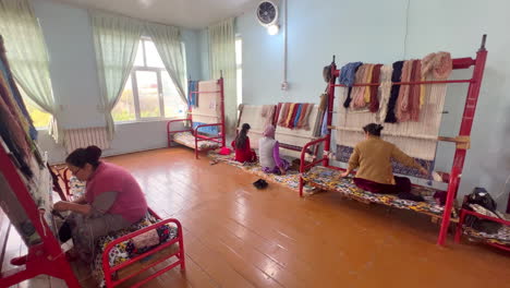 Local-women-knotting-a-handmade-carpet-in-Khiva,-Uzbekistan,-Central-Asia