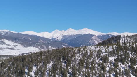 Drone-reveal-stunning-winter-mountain-landscape,-covered-by-snow-over-tree-line