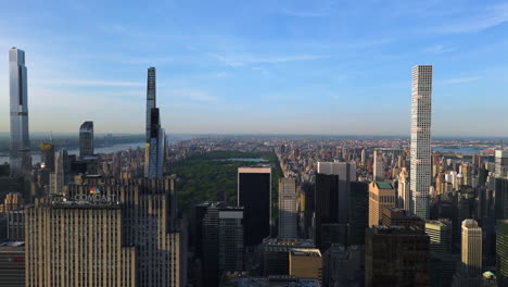 Disparo-De-Un-Dron-Volando-Frente-Al-Rascacielos-Del-Centro-De-La-Ciudad-Y-El-Parque-Central,-Puesta-De-Sol-En-Nueva-York