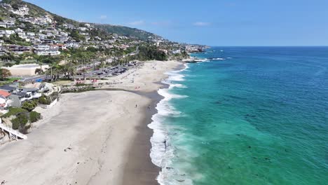 Wellen-Brechen-Am-Aliso-Beach-In-Südkalifornien,-Strahlend-Sonniger-Tag,-Große-Villen-Am-Strand-Und-In-Den-Hügeln,-Leute,-Die-Am-Strand-Entspannen,-60 fps