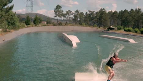 Wakesurfing-midair-skills-using-cable-in-lake,-summer-camping-vacation