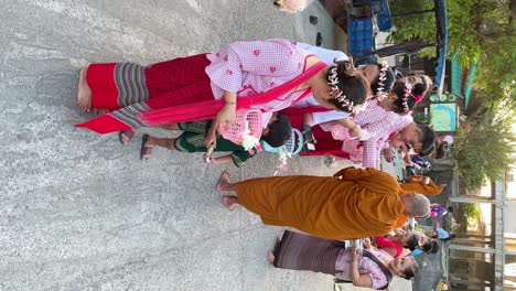 Vertical-view-of-a-group-of-people-in-Thai-native-dress-with-Buddhist-monks-sharing,-Thailand