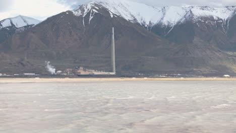 Wide-aerial-view-of-the-Great-Salt-Lake,-Utah-with-large-copper-mine-smelter-and-mountain-range-in-background