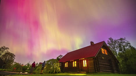 La-Gente-En-Una-Cabaña-De-Madera-Queda-Deslumbrada-Por-La-Aurora-Boreal-En-El-Cielo-Brillante-Y-Colorido---Lapso-De-Tiempo