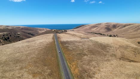 4k-drone-footage-of-a-camper-van-driving-along-a-long-straight-round-in-the-fleurieu-peninsula,-in-South-Australia