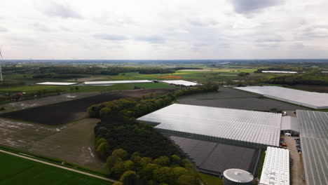 Massive-greenhouses-and-solar-panel-fields-in-Belgium,-aerial-drone-view