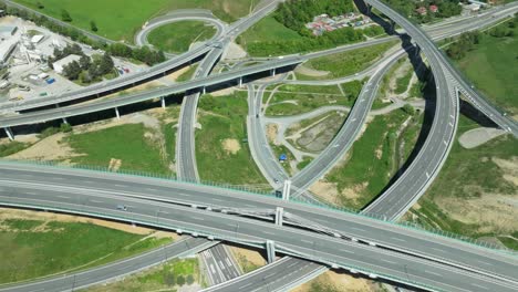 An-aerial-drone-captures-the-intricate-details-of-a-highway-junction,-showcasing-cars-navigating-complex-roundabouts-and-intersecting-roads