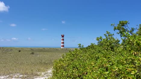 Beautiful-scenic-beach-with-red-and-yellow-stripes-Lighthouse-and-lushgreen-background,-Los-Roques