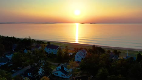 Vista-Aérea-Por-Drones-De-La-Hermosa-Puesta-De-Sol-En-La-Playa-En-Saco-Maine-Con-Casas-De-Vacaciones-Y-Colores-Reflejados-En-Las-Olas-Del-Océano-A-Lo-Largo-De-La-Costa-Atlántica-De-Nueva-Inglaterra