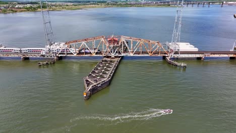 Ein-Zug-Fährt-über-Die-Alte-Zugbrücke-über-Den-Fluss-In-Perth-Amboy,-Davor-Ein-Fischerboot